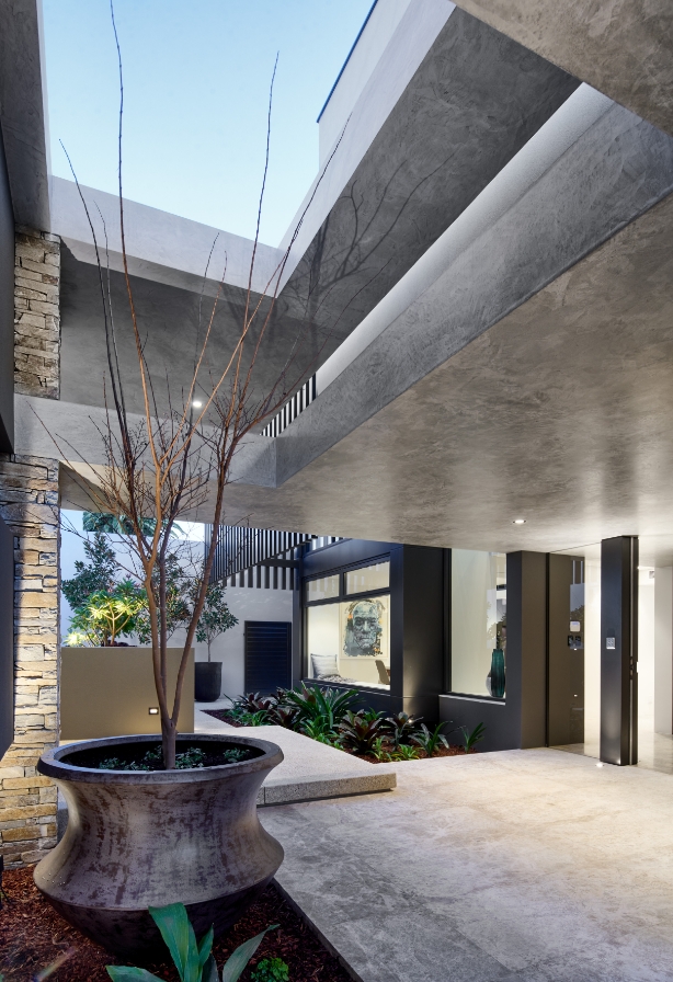 Modern home exterior with geometric architecture and courtyard.