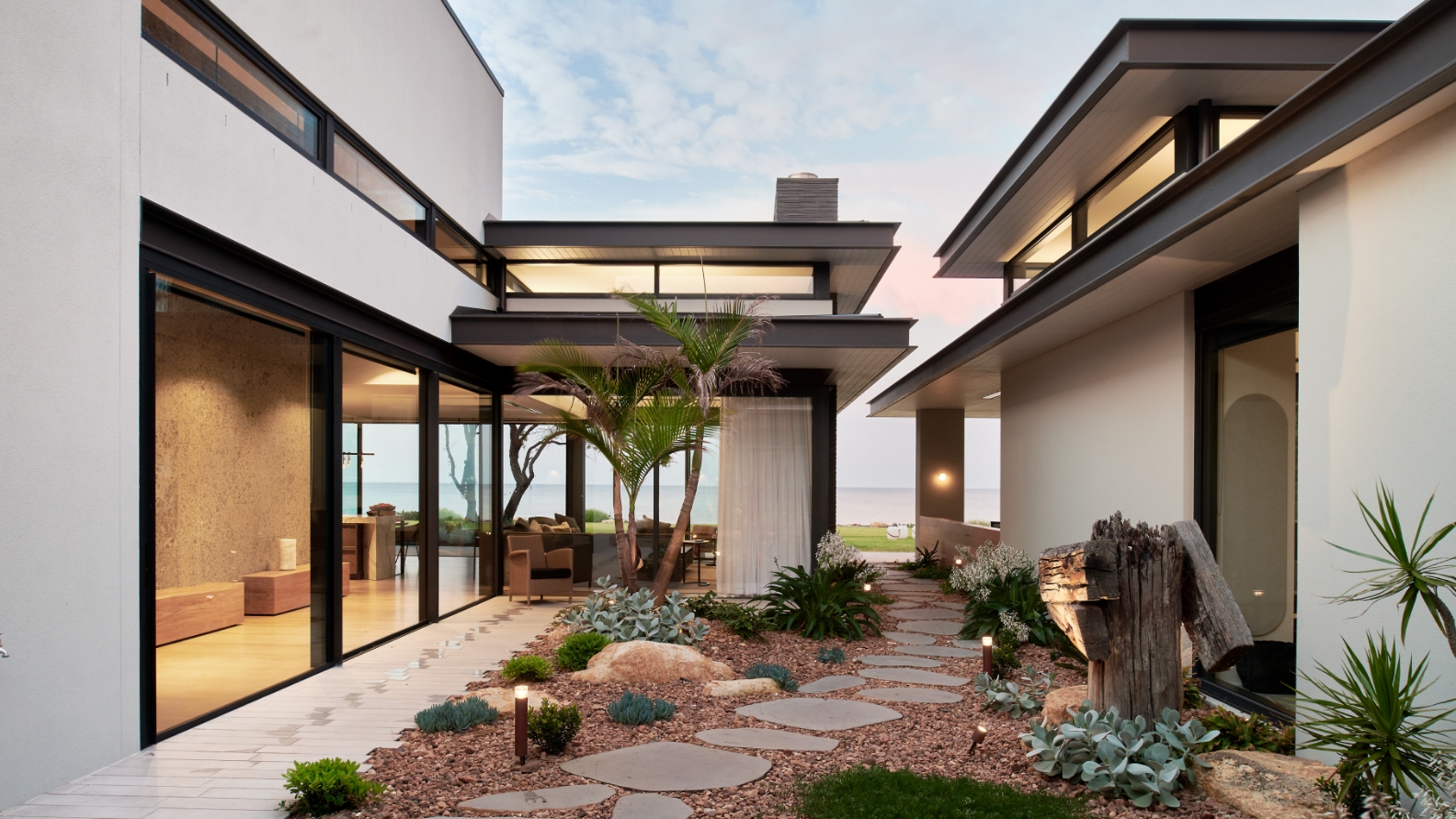 Modern beachfront house with landscaped garden at dusk