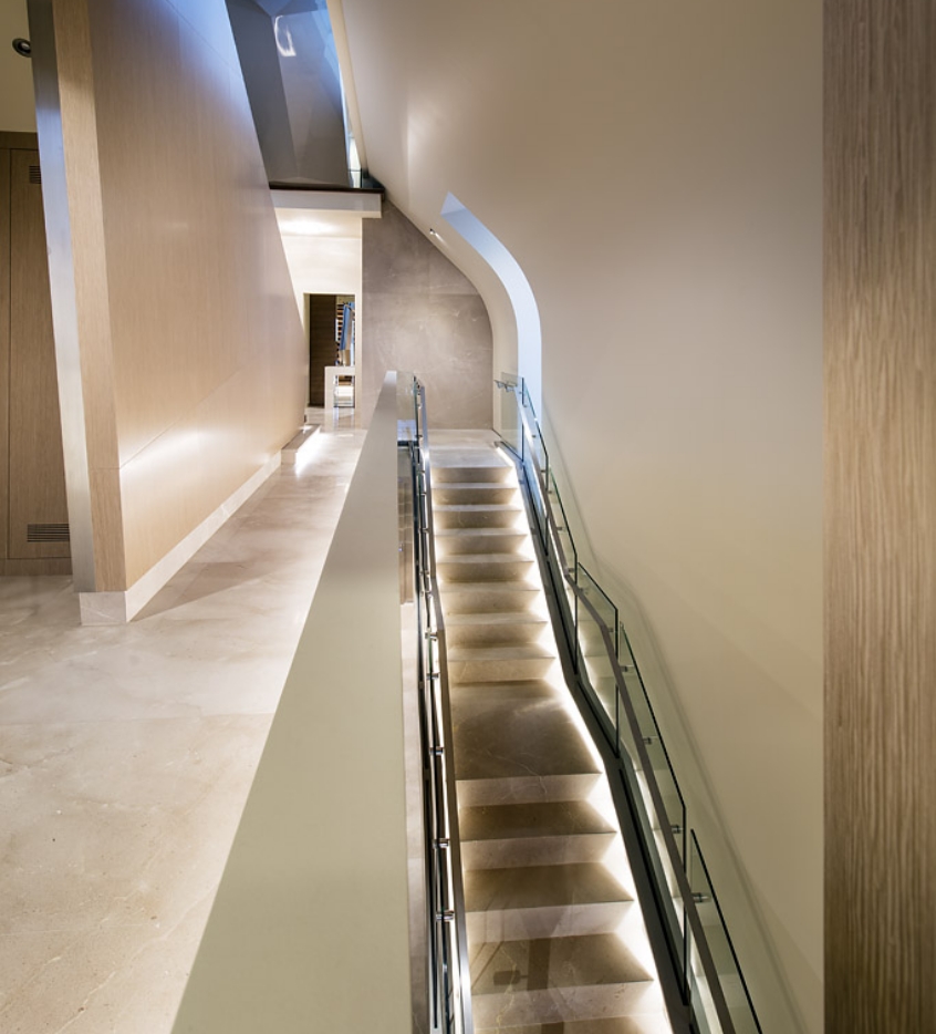 Modern interior staircase with lighting and curved wall.