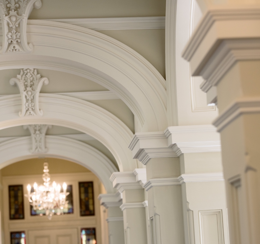 Elegant interior archways with ornate moldings and chandelier.