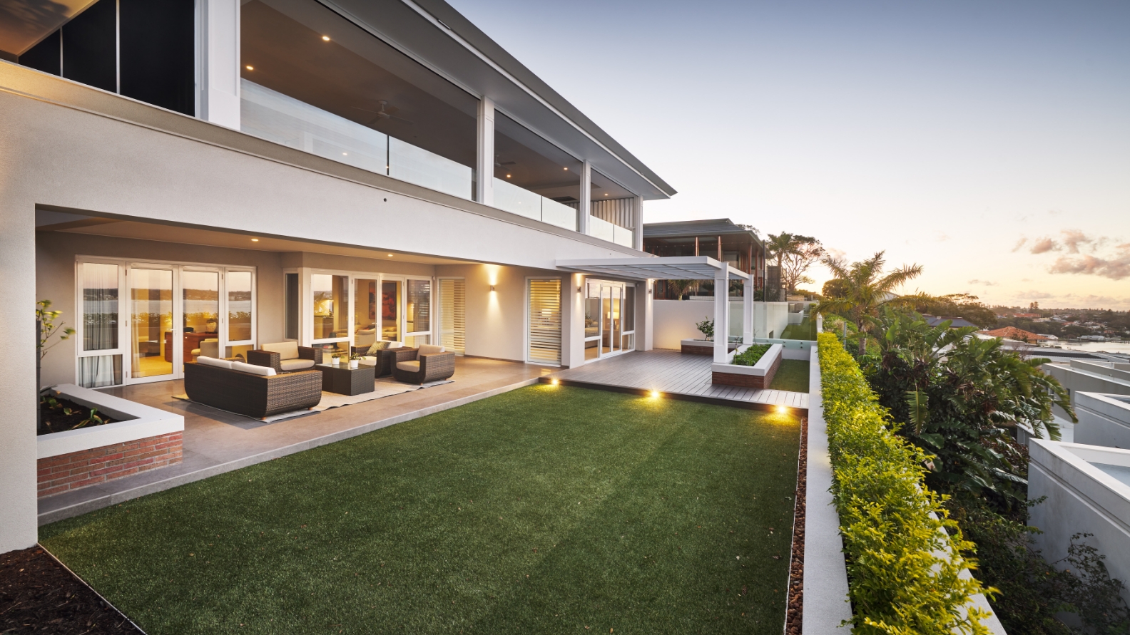 Modern luxury home exterior at sunset with outdoor lighting.