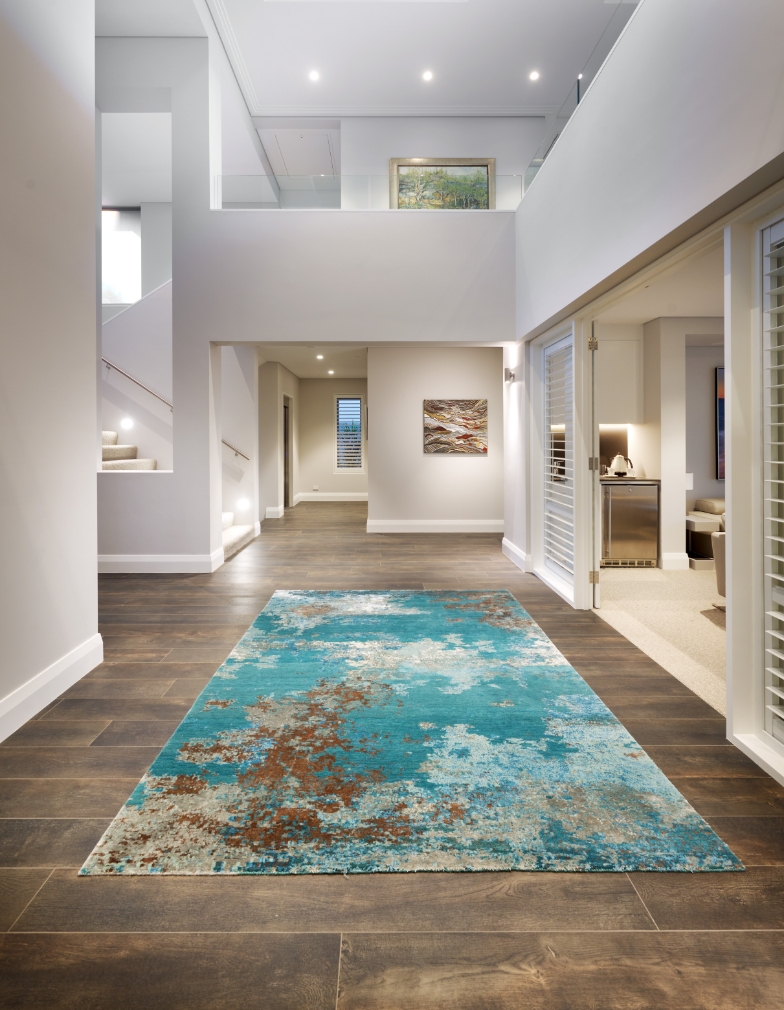 Modern home interior hallway with artwork and blue rug.