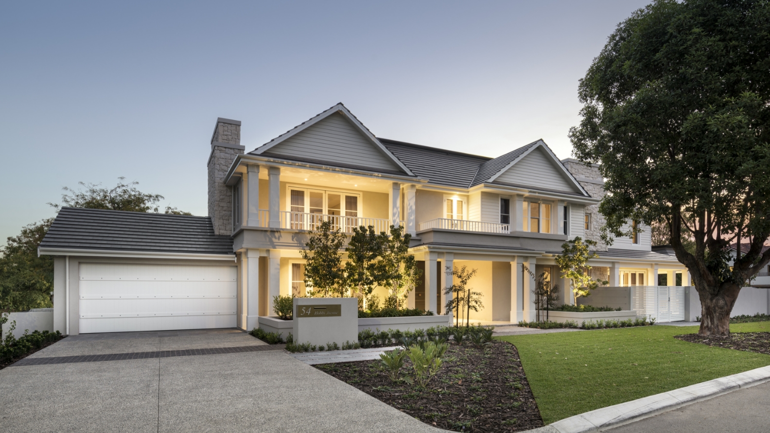 Elegant two-story suburban house at dusk with lighting.