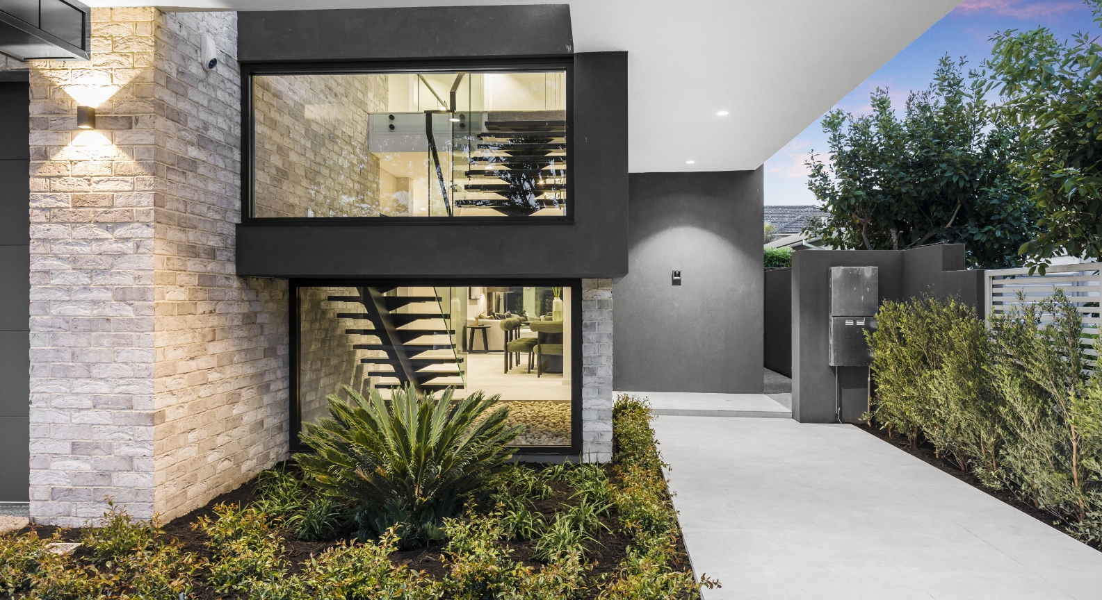 Modern house exterior at dusk with lighting.