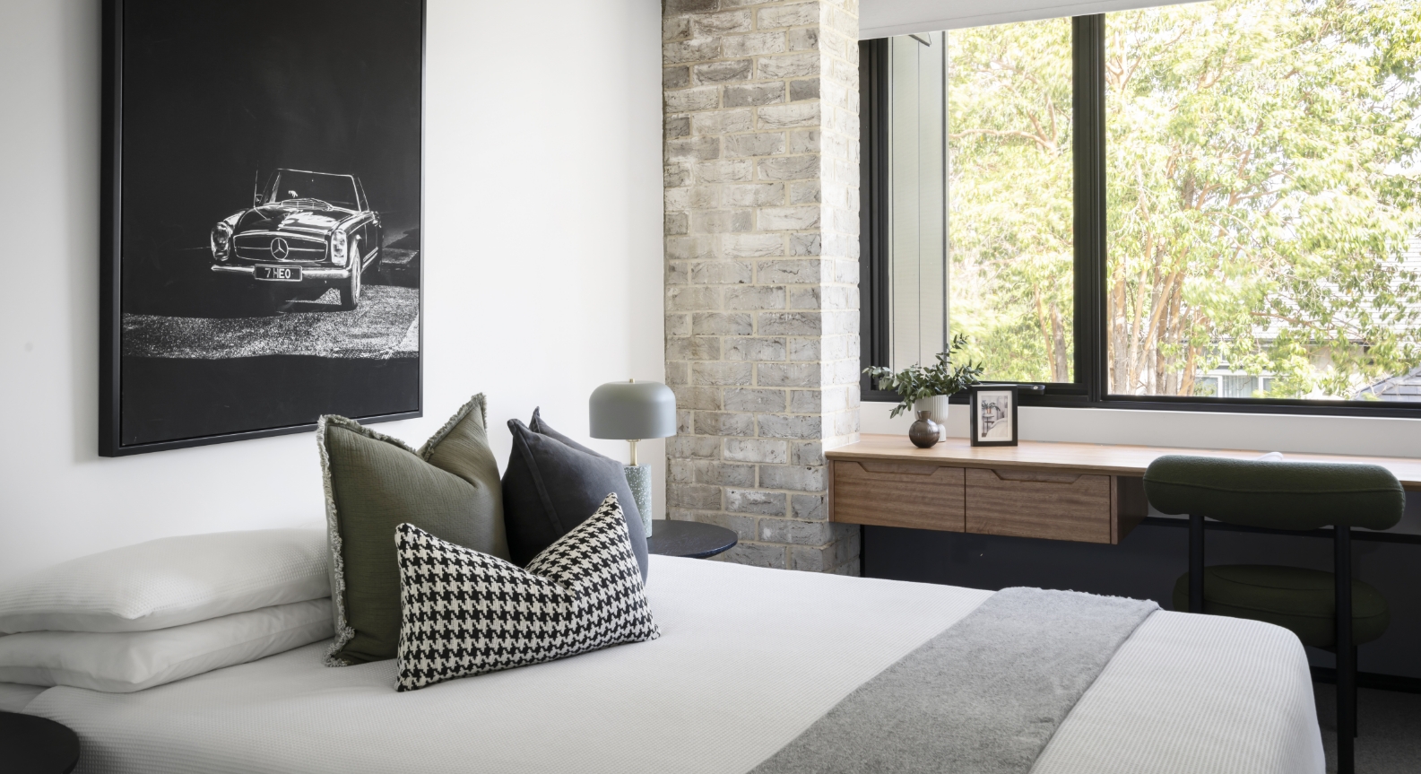 Modern bedroom with vintage car artwork and nature view.