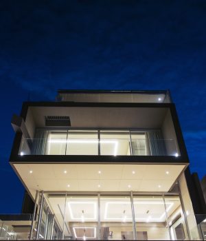Modern house lit up at night under blue sky.