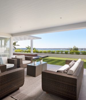 Luxury patio with wicker furniture overlooking a scenic lake.